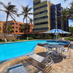 a swimming pool with chairs and a table and an umbrella at Tucacas, Frente al Mar, Piscina y Playa Privada in Tucacas