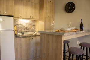 a kitchen with a counter with bar stools and a clock at Annis House in Epanomi