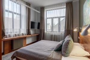 a bedroom with a bed and two large windows at Roze Brīvzemnieka Apartments in Liepāja +21 photos