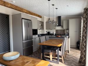 a kitchen with a wooden table and a dining room at Luxury Lodge Retreat with Hot Tub - Stewarts Resort 19 in St. Andrews +3 photos