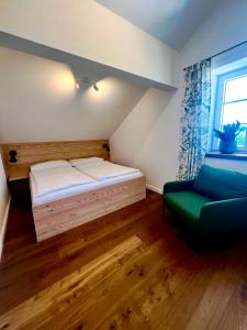 a small bedroom with a bed and a green chair at Wohnen am Penzkofergut in Feichten