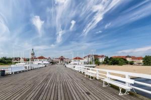 a pier with white benches on the beach at Sopot Modern Apartments 3 in Sopot +6 photos