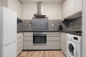 a kitchen with white cabinets and a washer and dryer at BTS 2 Bed Apart Inverness Centre in Inverness +16 photos