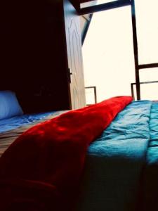 une chambre avec un lit avec une couverture rouge dessus dans l'établissement BlackBuck Cottage, à Jyotirmath