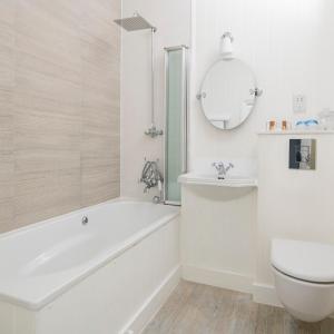 a white bathroom with a tub and a toilet at Harbour Hotel & Spa St Ives in St Ives