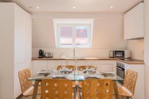 una cucina con tavolo in vetro e sedie di Appartement 3 chambres en centre ville et proche métro a Croix