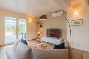 a living room with a white couch and a tv at Villa Cosima in Bellagio with Private Pool in Bellagio