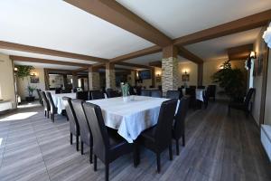 a dining room with a white table and black chairs at Pensiunea Bergtal in Râşnov