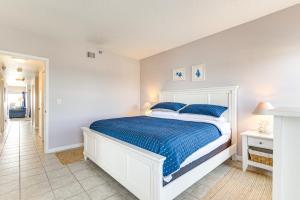 a bedroom with a white bed with blue sheets at Beachfront New Smyrna Condo: 1 Mi to Flagler Ave in New Smyrna Beach