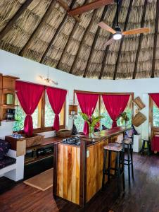 a kitchen with a bar in a room with red curtains at Framadani estate - Villa with a pool and Or thatch roof Cabin in San Ignacio