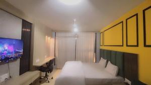 ジャイプールにあるUpasana Luxurious Apartmentのベッド、机、テレビのある寝室 +2枚の写真
