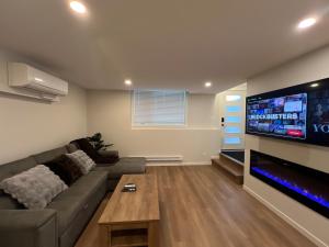 Una sala de estar con un sofá y un televisor de pantalla plana. en Cozy 2 bedrooms Suite Near Calgary Airport Sleeps 6, en Calgary
