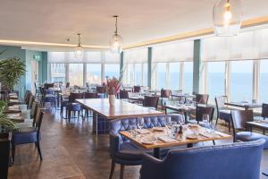 a restaurant with tables and chairs and windows at Harbour Hotel & Spa St Ives in St Ives