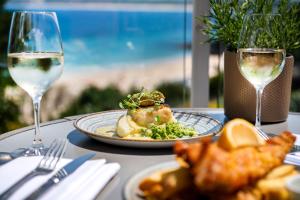 a table with a plate of food and glasses of wine at Harbour Hotel & Spa St Ives in St Ives