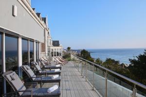 a row of lounge chairs on a balcony overlooking the ocean at Harbour Hotel & Spa St Ives in St Ives