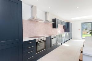 a kitchen with black cabinets and pink tiles at Spacious House Private Parking & Garden in Gloucestershire