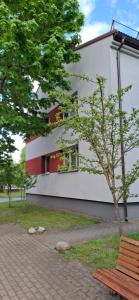 a building with a tree in front of a bench at Pas Dianą in Jurbarkas