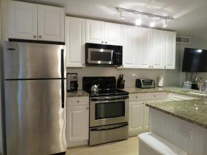 a kitchen with white cabinets and a stainless steel refrigerator at Driftwood Condo 15 in Cape May