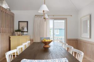 a dining room with a table with chairs and a bowl of fruit at Stylish Home with Pool Hot Tub & Walk to Beach in Duck