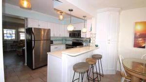 Una cocina con nevera y una mesa con taburetes. en Capers302, en Cape May