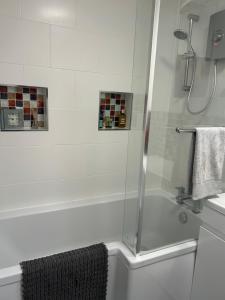 a shower with a glass door next to a tub at Large room, superking bed and en-suite wet room in Southbourne