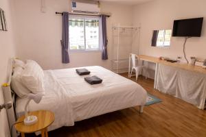 a bedroom with a bed and a desk with a television at Jida Place in Chiang Mai