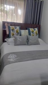 Un dormitorio con una cama con almohadas y una ventana. en Palm Shade Gigiri, en Nairobi