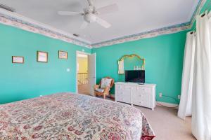 1 dormitorio con paredes azules, 1 cama y espejo en Island Sunrise, en Dauphin Island