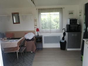 a kitchen with a table and a microwave and a window at Mobilhome cool in Pleurtuit
