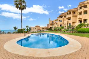 a swimming pool in front of a building with a palm tree at Pilar Luxury Apartment in Benalmádena