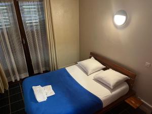 a small bed with a blue blanket and white pillows at Hôtel le belledonne in Le Bourg-dʼOisans
