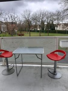 two red chairs and a white table in front of a window at Logement T2 tres propre in Cergy