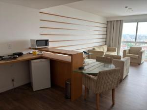 a room with a desk and a table and a living room at Flat Golden Macaé vista mar in Macaé