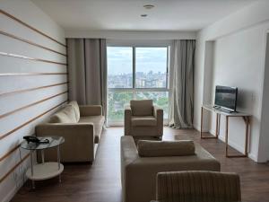 a living room with a couch and chairs and a tv at Flat Golden Macaé vista mar in Macaé