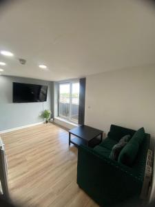 a living room with a green couch and a flat screen tv at Modern 1-Bed Flat with Balcony in Bradford