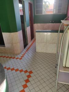 a bathroom with a white tiled floor with orange and green at Motel ritz in Lavras