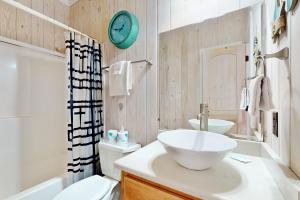 ein Badezimmer mit einem Waschbecken und einer Uhr an der Wand in der Unterkunft Beach Haven in Dauphin Island + 18 Fotos