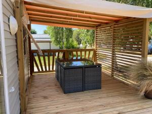 a wooden deck with a pergola and a table at Camping le Ranch - Naujac sur Mer in Naujac-sur-Mer