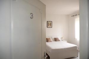 a white bedroom with a bed and a window at Tenuta Maison Angelina in Formia