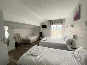 una camera d'albergo con due letti e una televisione di Hôtel L'Oustalet a Font-Romeu-Odeillo-Via