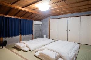a bedroom with two beds in a room with wooden ceilings at kumihimo kobe in Wada