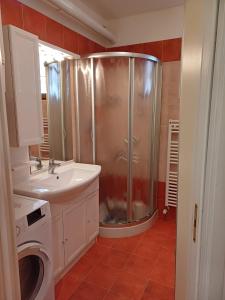 a bathroom with a shower and a sink and a washing machine at Gli appartamenti in piazza in Calalzo