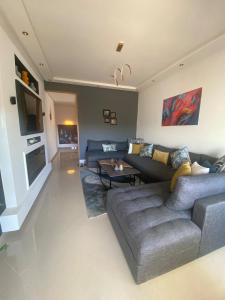 a living room with a gray couch and a tv at Luxury apartment in Asilah Marina Golf in Asilah