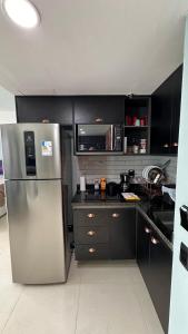 a kitchen with a stainless steel refrigerator and black cabinets at Flat Tropical Executive in Manaus