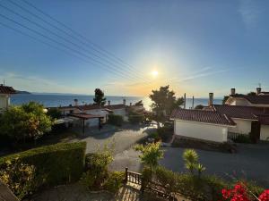 a view of a house with the sun setting over the ocean at Seafront Private Apartment in Neos Marmaras