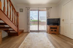 a living room with a tv and a sliding glass door at Tigh na Drochaid, Glen Nevis - Entire Apartment in Fort William