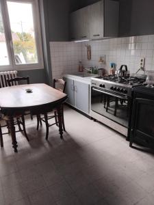 a kitchen with a table and a stove at La Petite Maison du Sculpteur in Saint-Saud-Lacoussière