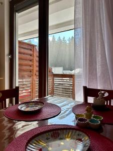 a dining room table with two plates and a window at Clabucet View Apartment in Predeal