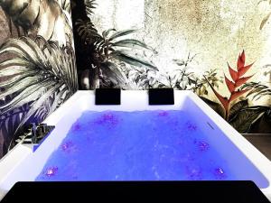 a bath tub with blue water in a room with plants at Heliconia in Bari