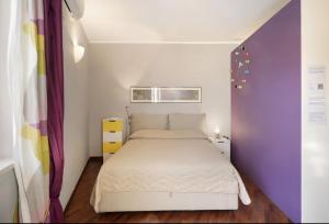 een kleine slaapkamer met een wit bed en een paarse muur bij Central Apartment in Salerno